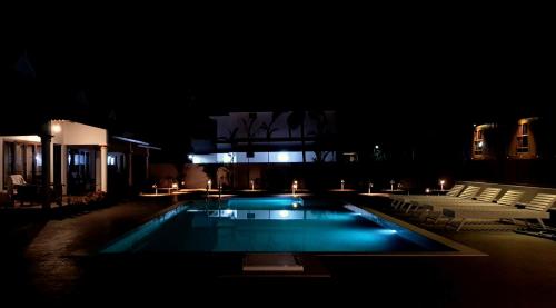 a swimming pool at night with chairs and a building at Marari Green Villas in Mararikulam