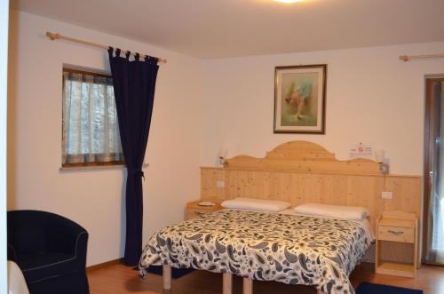 a bedroom with a bed and a chair and a window at Agritur All'Olivo in Faver