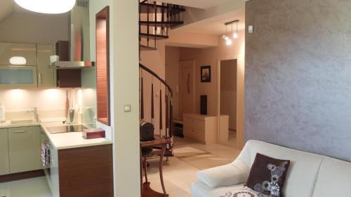 Una sala de estar con un sofá blanco y una cocina. en Apartament Parkowa Polana, en Polanica-Zdrój