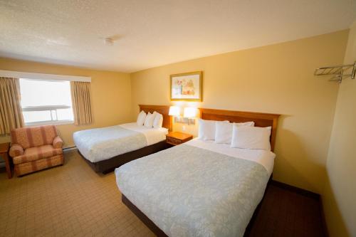 ein Hotelzimmer mit 2 Betten und einem Stuhl in der Unterkunft Midway Motel in Brandon