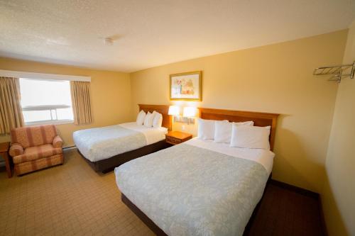 a hotel room with two beds and a chair at Midway Motel in Brandon