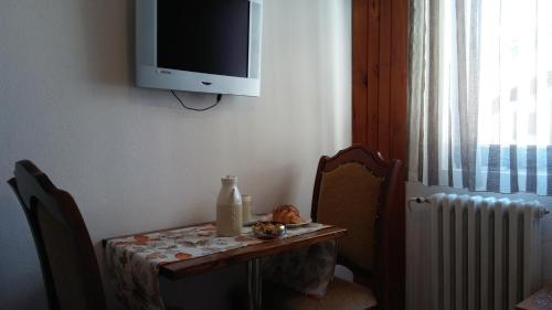a table with a tv on the wall and a table with a tableablish at Guest house Villa Castio in Petrovac na Moru