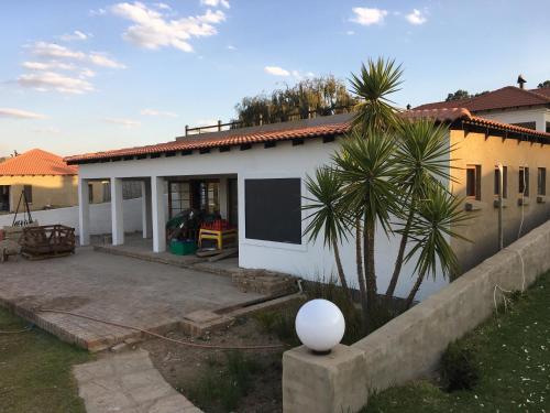 a white house with a palm tree in front of it at Bottom of Boden in Benoni