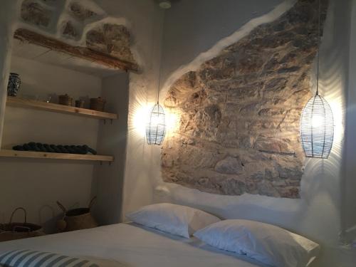 a bedroom with a stone wall and a bed with two pillows at Astrofegia guest house in Donoussa