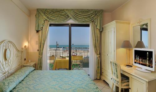 a bedroom with a bed and a desk and a window at Hotel Bridge in Bellaria-Igea Marina