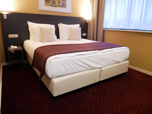 a hotel room with a large bed in a room at Hotel het Oosten in Alphen aan den Rijn