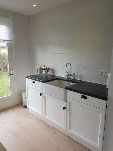a white kitchen with a sink and a counter at Heerlijk aan Zee in Julianadorp