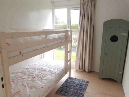 ユリアーナドルプにあるHeerlijk aan Zeeのベッドルーム(二段ベッド1組、窓付)
