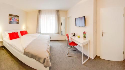 Schlafzimmer mit einem Bett, einem Schreibtisch und einem TV in der Unterkunft Weyher Aparthotel in Weyhe