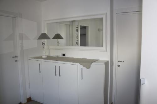 bagno bianco con lavandino e specchio di Appartamento Alla Fonte a Madesimo