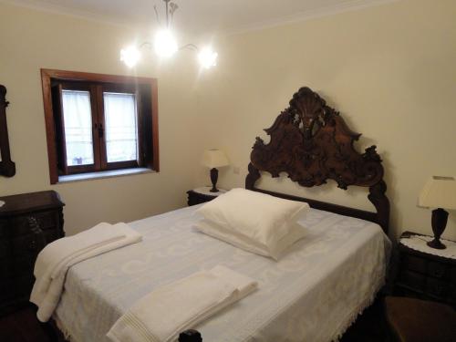 - une chambre avec un grand lit et une tête de lit en bois dans l'établissement Refúgio da Geira, à Campo do Gerês