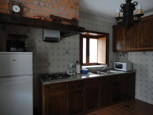 a kitchen with a stove and a sink and a refrigerator at Melodia do Campo in Terras de Bouro