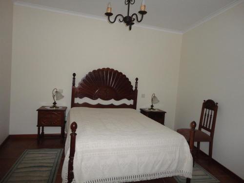 a bedroom with a bed and two tables and a chandelier at Melodia do Campo in Terras de Bouro