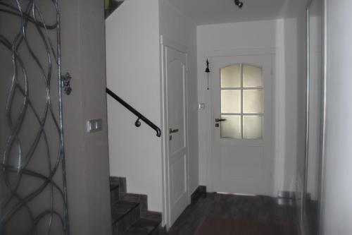 a hallway with a white door and a window at Pokoje Gościnne Сisza in Białowieża