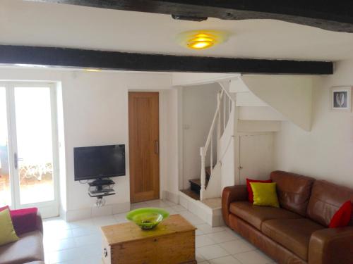 a living room with a couch and a tv at The Heart of Sainte Mere Eglise in Sainte-Mère-Église