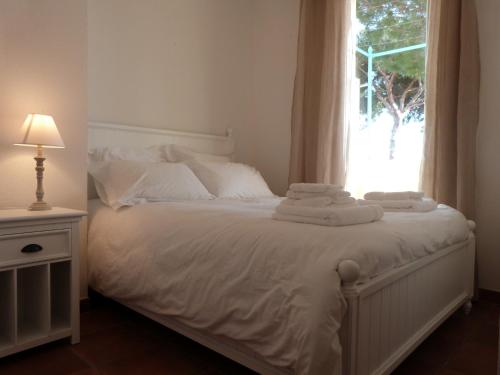 une chambre avec un lit avec des draps blancs et une fenêtre dans l'établissement Jardins du Port Les Issambres - Meublé de Tourisme - Front de mer - Clim, à La Garonnette-Plage