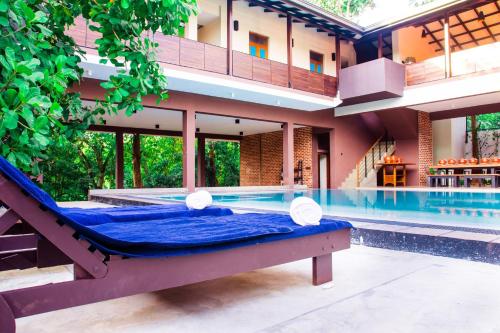 a pool with a bed in front of a building at Roshara Nalla in Giriulla