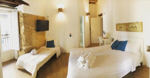 Bedda Mari Rooms & Suite في باليرمو: غرفة نوم بسريرين بيض واريكة