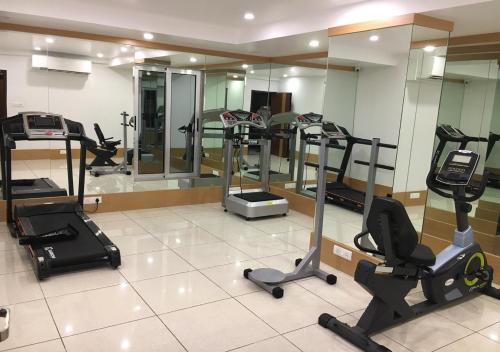 a gym with several treadmills and elliptical machines at Hotel Orange International in Surat