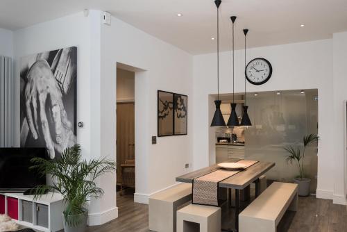 a dining room with a table and a clock on the wall at Number 19 Chapel Court in Leamington Spa