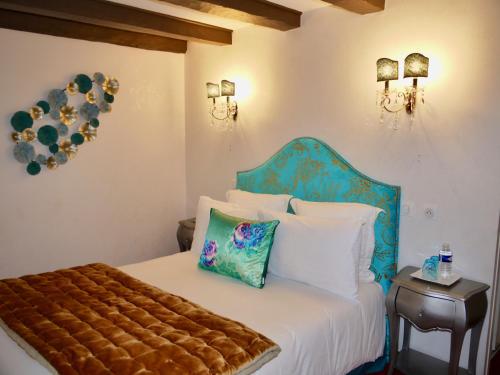 a bedroom with a bed with a blue headboard and pillows at Le Chapeau Rouge in Lusignan