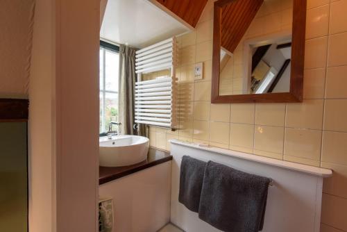een badkamer met een wastafel en een spiegel bij Hotel De Koegelwieck Terschelling in Hoorn