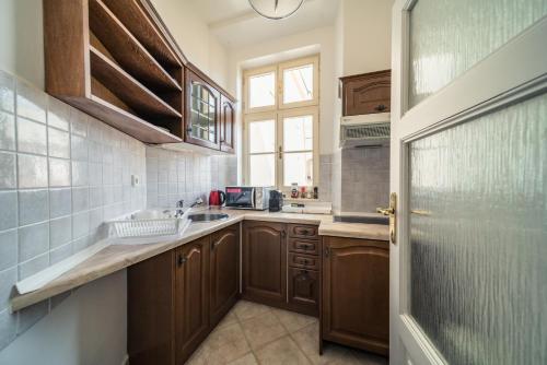a kitchen with wooden cabinets and a sink and a window at St. George Apartments in Prague