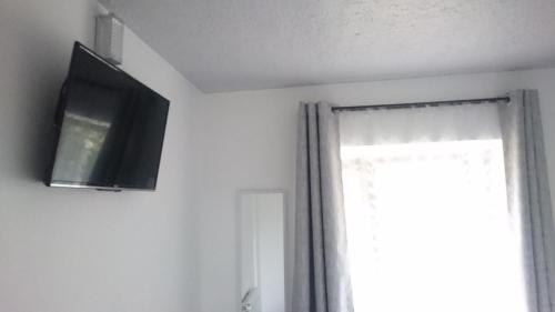 a television hanging on a wall next to a window at Hotel Aysen Austral in Puerto Aisén
