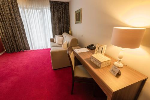 a room with a desk with a lamp and a couch at Hotel Boutique Belvedere in Sinaia