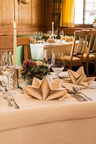 a table with a white table cloth with wine glasses and napkins at Hotel Zum Pinzger in Stumm