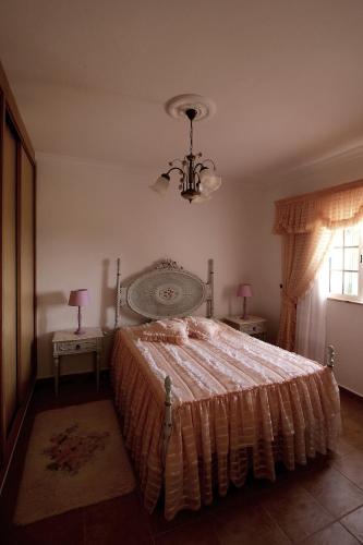 a bedroom with a bed and two tables and a chandelier at Monte Belo Romão in Olhão