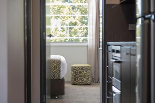 a kitchen with a window and a stool in front of it at Quest Ponsonby Serviced Apartments in Auckland