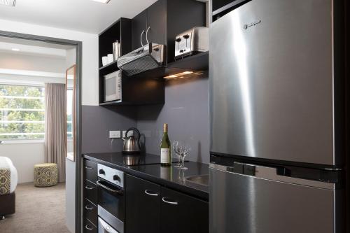 a kitchen with black cabinets and a stainless steel refrigerator at Quest Ponsonby Serviced Apartments in Auckland