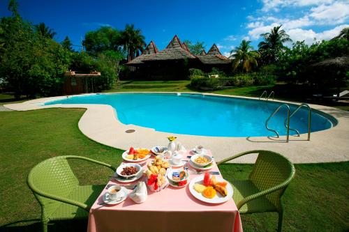 a table with food on it next to a pool at Badian Island Wellness Resort in Badian
