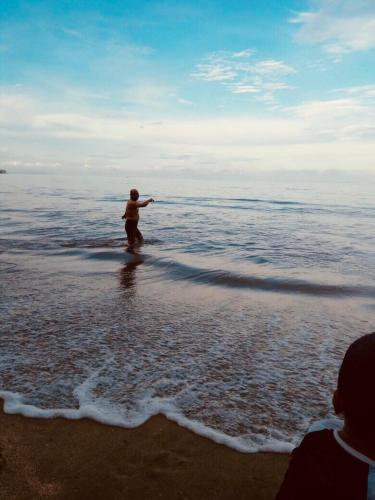 a man standing in the water at the beach at Lippo Carita Beach Utara Condo Noah in Carita