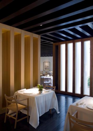a dining room with two tables and chairs and windows at Atrio in Cáceres
