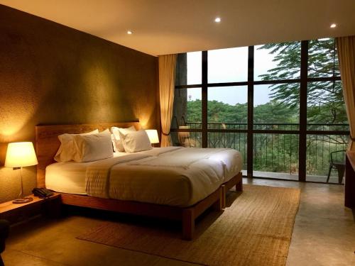 a bedroom with a bed and a large window at Inchantreedoopool in Kanchanaburi