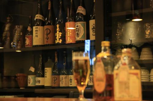 a glass of wine in front of a shelf of bottles at Hotel New Station in Matsumoto