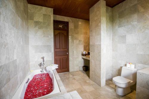 a bathroom with a toilet and a bath tub at Vision Villa Resort in Keramas