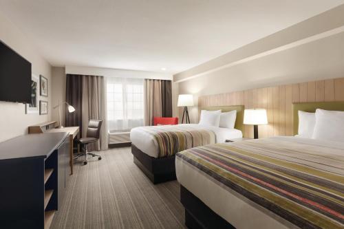 a hotel room with two beds and a desk at Country Inn & Suites by Radisson, Bakersfield, CA in Bakersfield