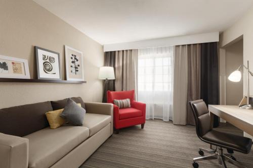 a living room with a couch and a red chair at Country Inn & Suites by Radisson, Bakersfield, CA in Bakersfield