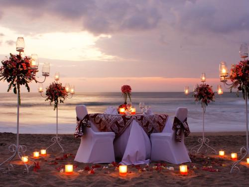 a table with candles on a beach with the ocean at Legian Beach Hotel in Legian