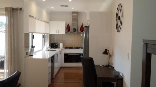 a kitchen with white cabinets and a wooden table with a tableablish at Carpe Diem South #3 in Busselton