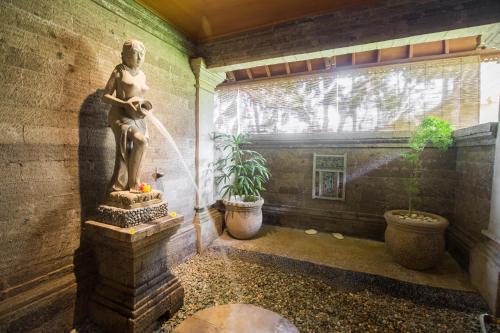 a statue of a girl drinking from a fountain at Vision Villa Resort in Keramas