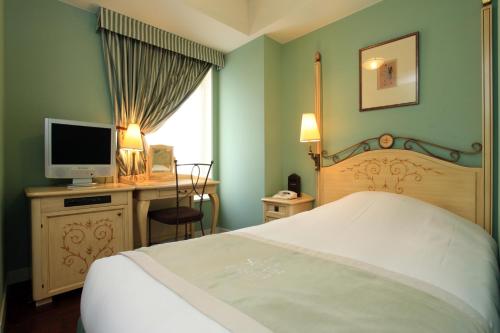 1 dormitorio con 1 cama y escritorio con TV en Hotel Monterey Lasoeur Ginza, en Tokio