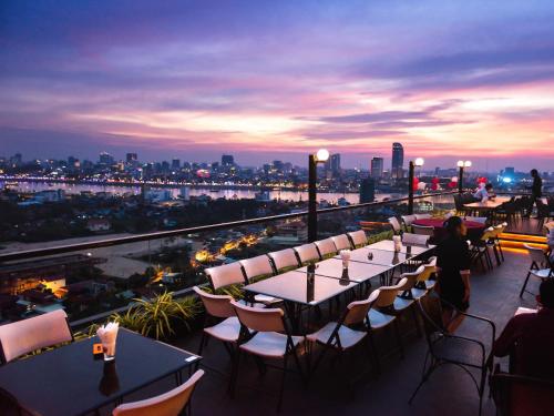 a rooftop bar with tables and chairs and a view of the city at MekongView 1 CondoTel in Phnom Penh