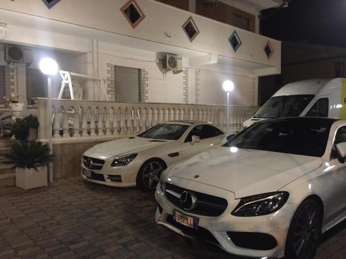 two white cars parked in a parking lot at Hotel La Maison Delle Terme in Tivoli Terme