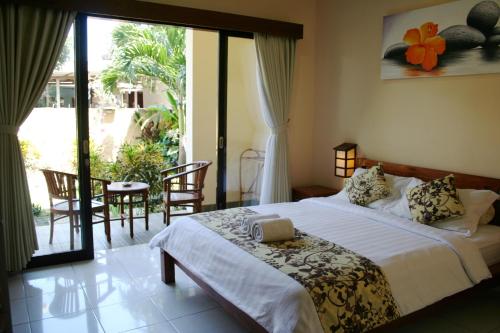 a bedroom with a bed and a sliding glass door at Betesda Guest House in Canggu