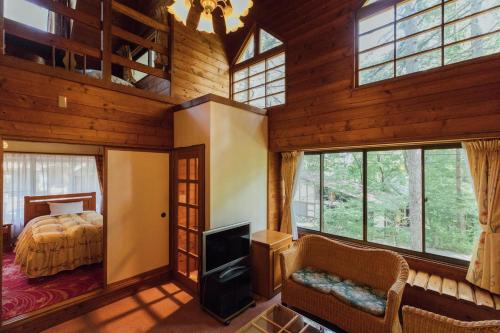 a bedroom in a log cabin with a bed and a tv at Izumigo AMBIENT Yatsugatake Cottage in Hokuto