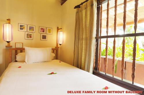 a bedroom with a bed and a large window at Hoi An Pho Library Hotel in Hoi An